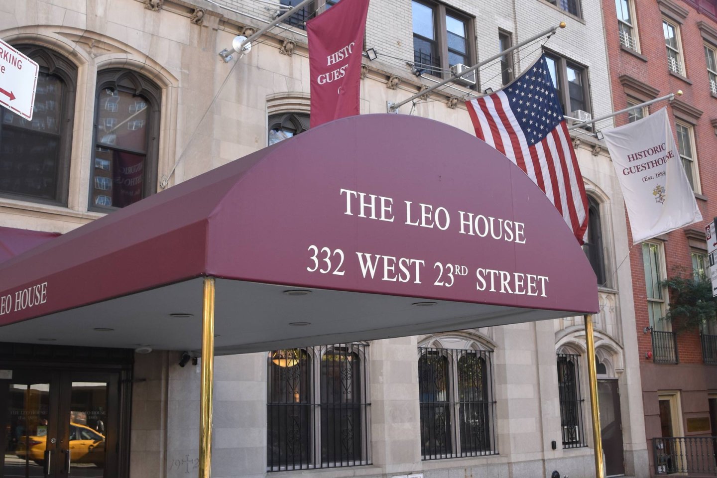 A maroon awning reading "THE LEO HOUSE 332 WEST 23RD STREET" is shown outside a building. American flags and banners labeled "HISTORIC GUESTHOUSE" are visible in the background.