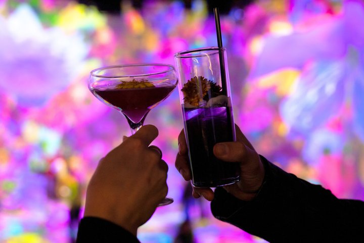 Two people clinking cocktails at ARTECHOUSE NYC