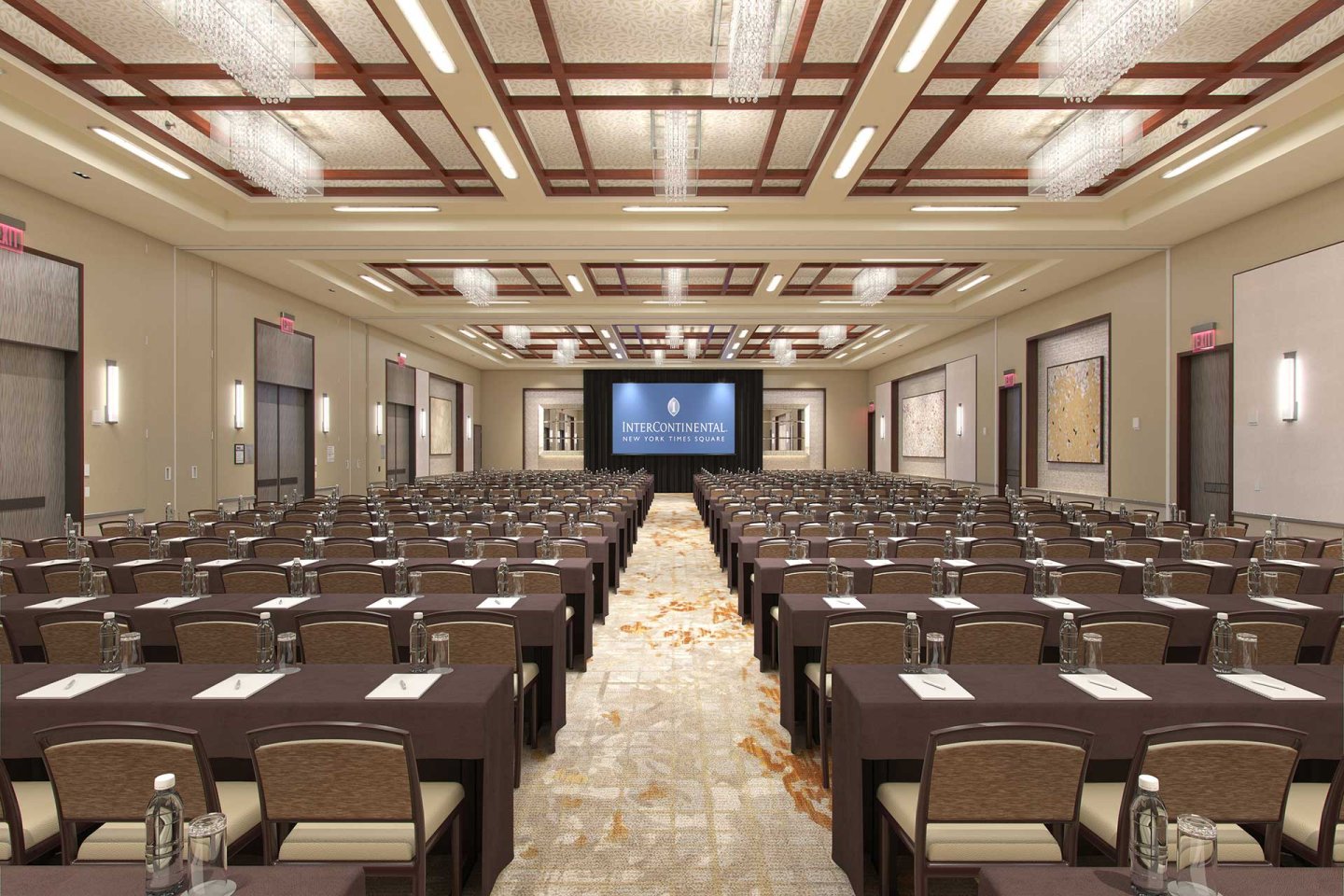 A large, elegant conference room set up classroom-style with rows of tables and chairs facing a stage and large screen displaying “InterContinental.” Notepads and water bottles are placed on each table.