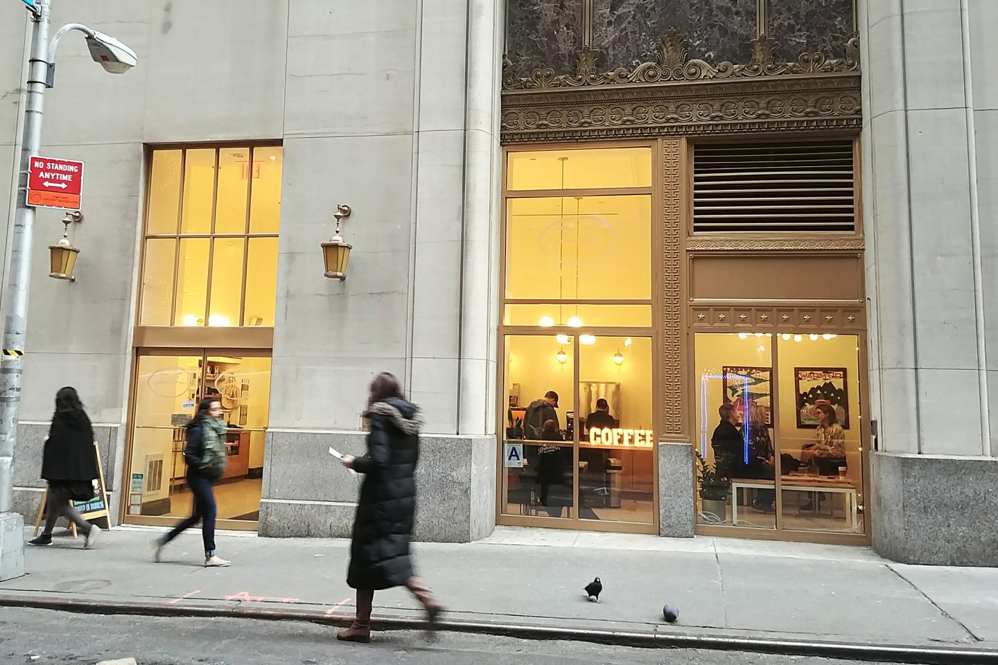 Cafe Grumpy coffee shop exterior shot on Stone Street in Manhattan with customers inside and people walking by on the street
