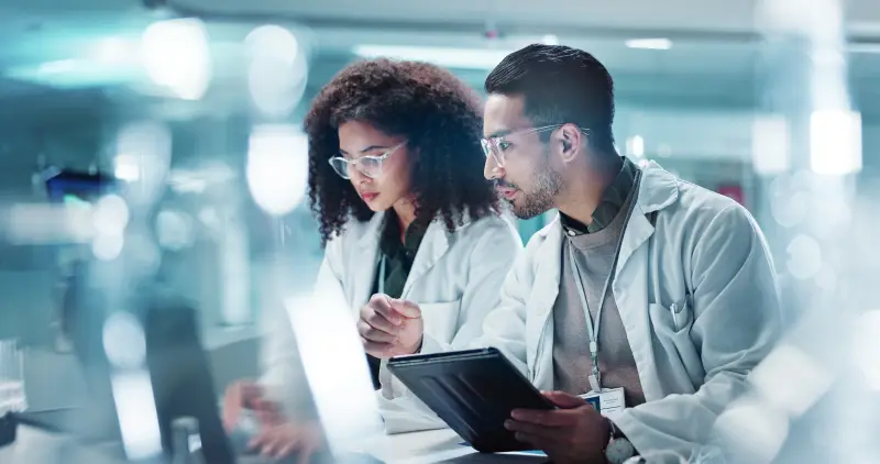 Science, teamwork and laptop with laughing in laboratory for communication, pharmaceutical review or planning. Employees, collaboration and technology for research, discussion and digital analysis.