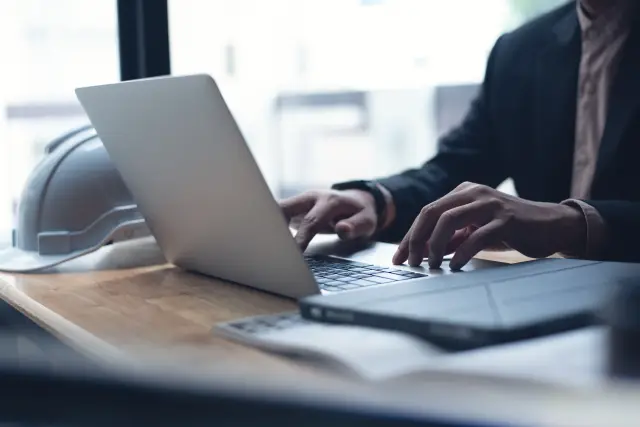 Male engineer or architecture man working with autocad program on laptop computer with blue print and digital tablet on office desk, close up