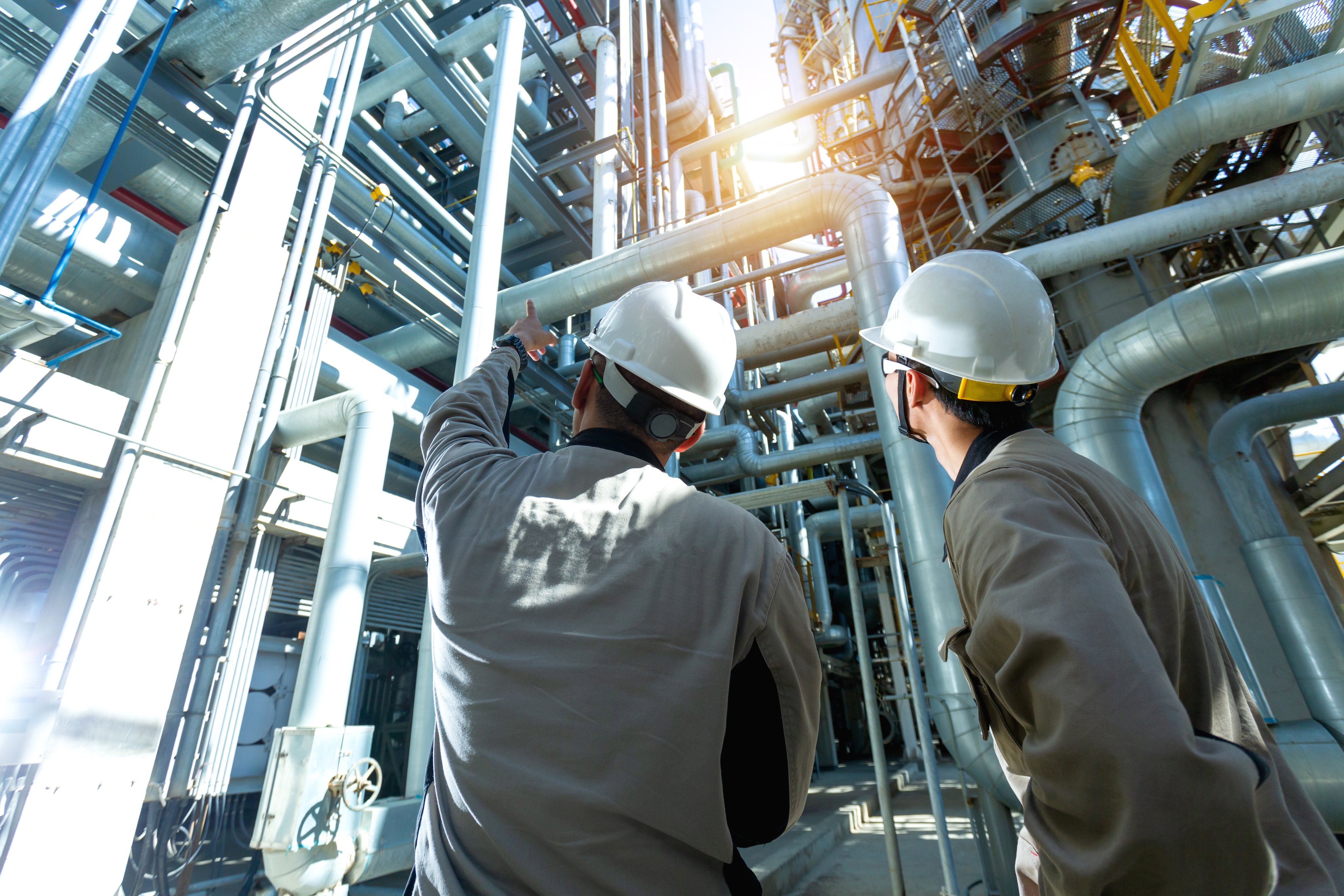 Industrial engineer or worker checking pipeline at oil and gas refinery plant form industry zone with sunrise and cloudy sky, oil and gas Industry concept.