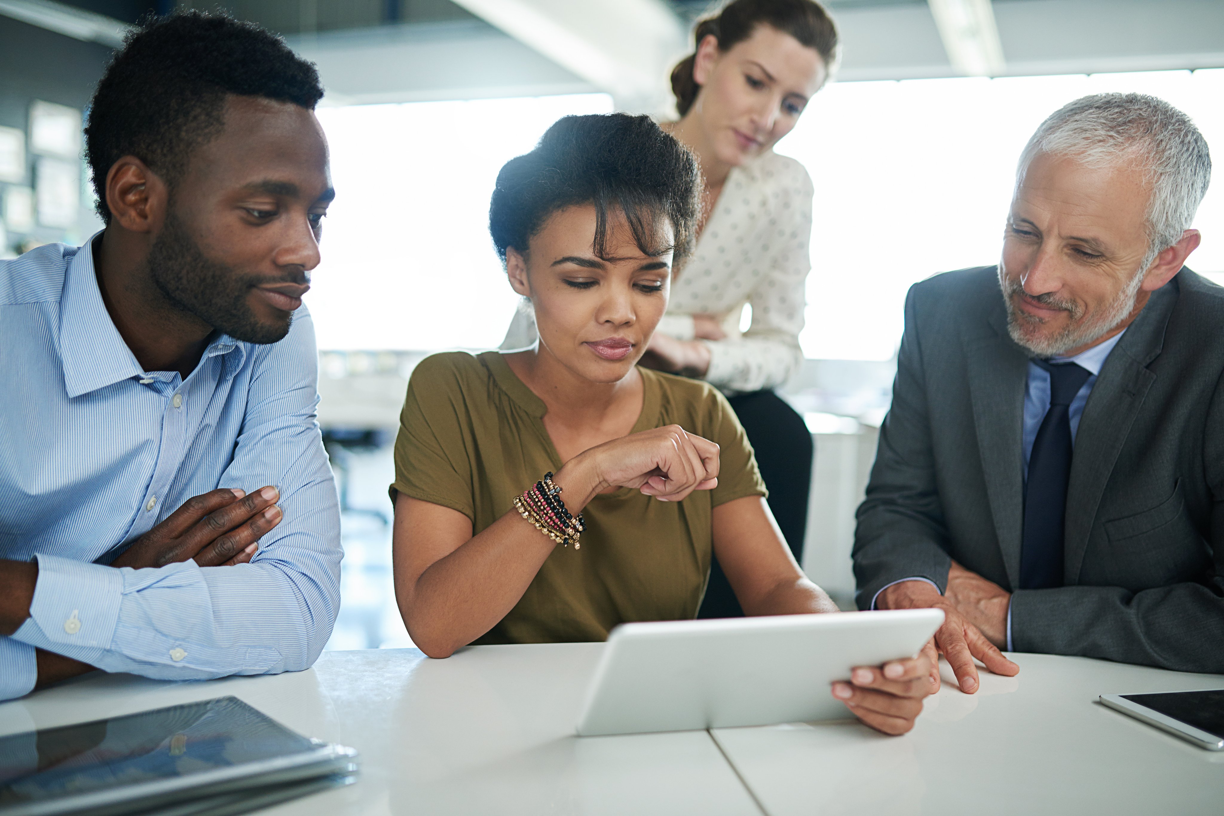 Shot of a group of businesspeople talking together over a digital tablet in an office.