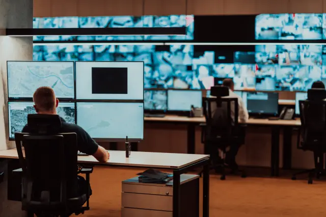 Male security operator working in a data system control room offices Technical Operator Working at workstation with multiple displays, security guard working on multiple monitors Male computer opera. High quality photo