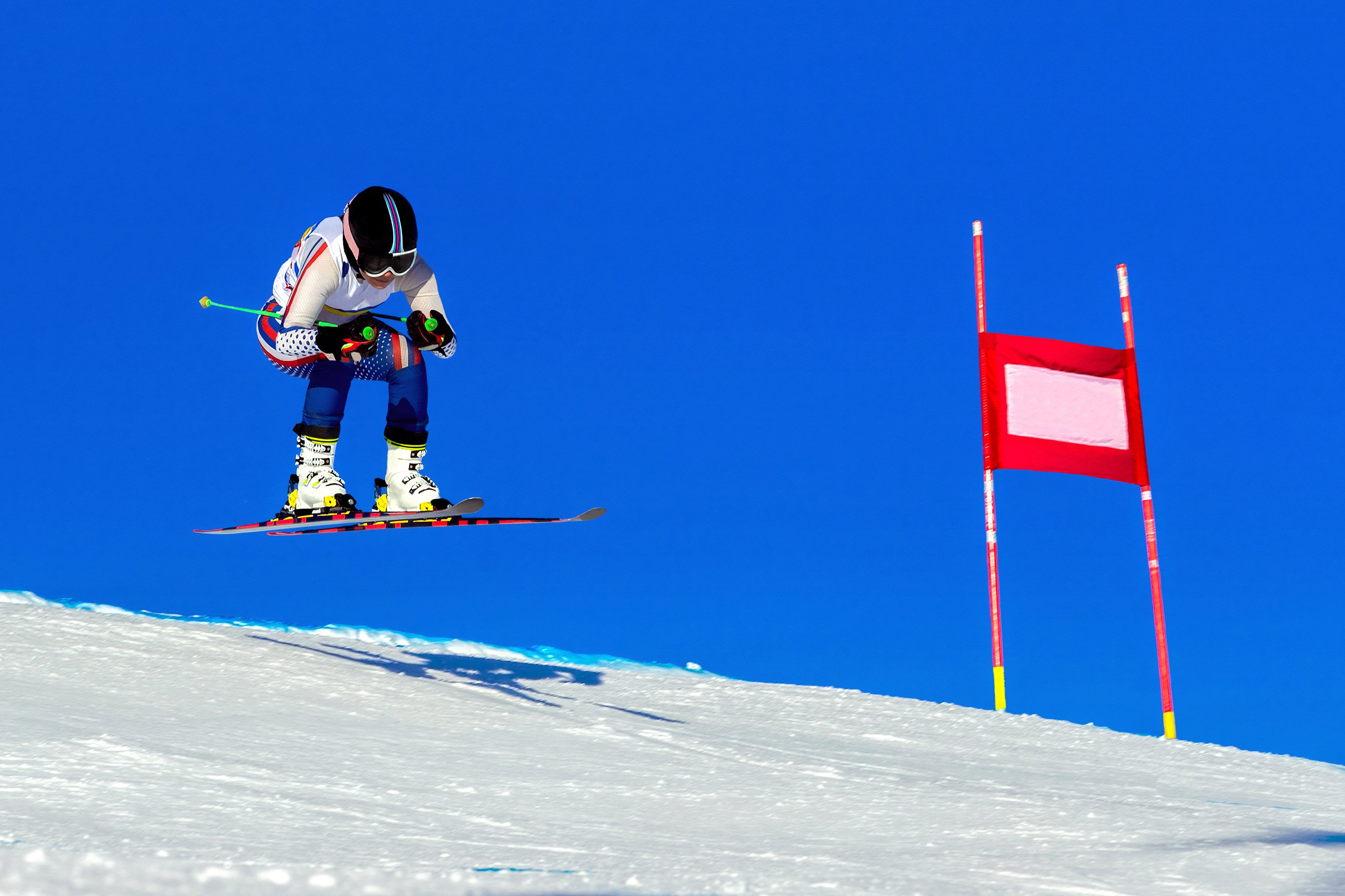 female skier athlete on alpine skiing track, snowy slope on blue sky background, winter sports games