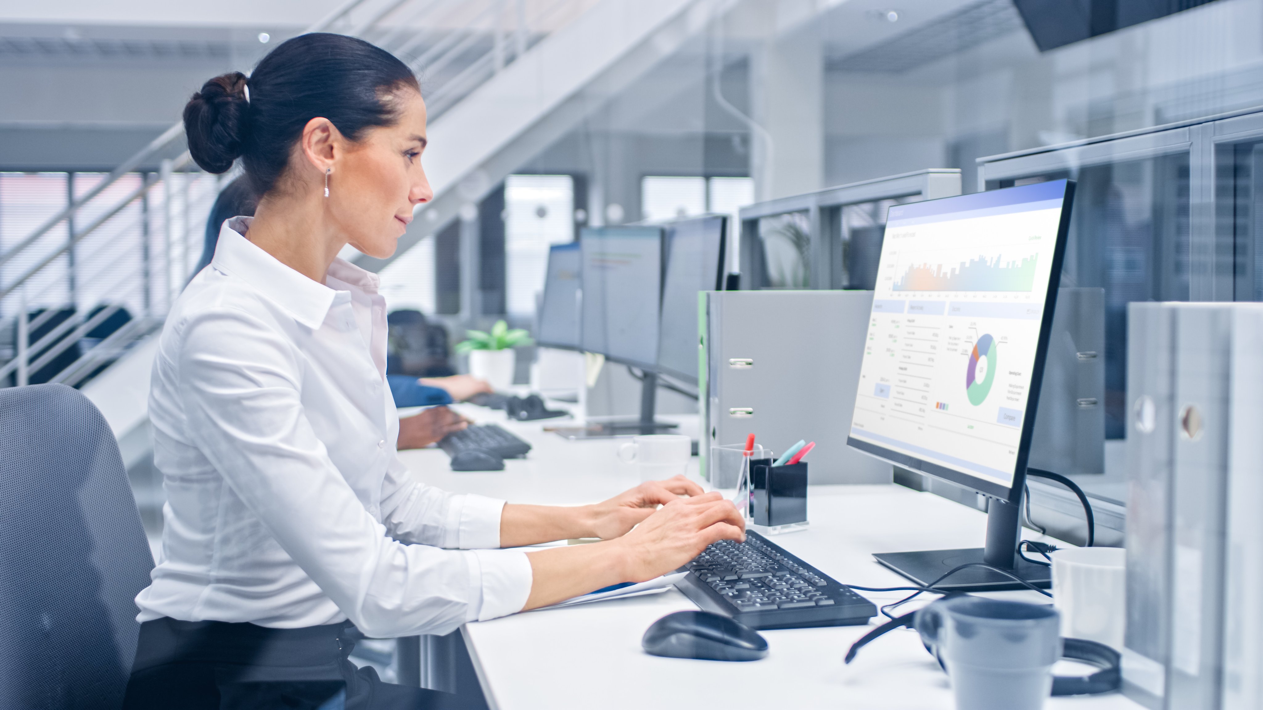 Young Handsome Female Manager is Working on Her Personal Computer with Data Statistics, Charts and Graphs. Diverse and Motivated Business People Work in Bright Modern Open Office.