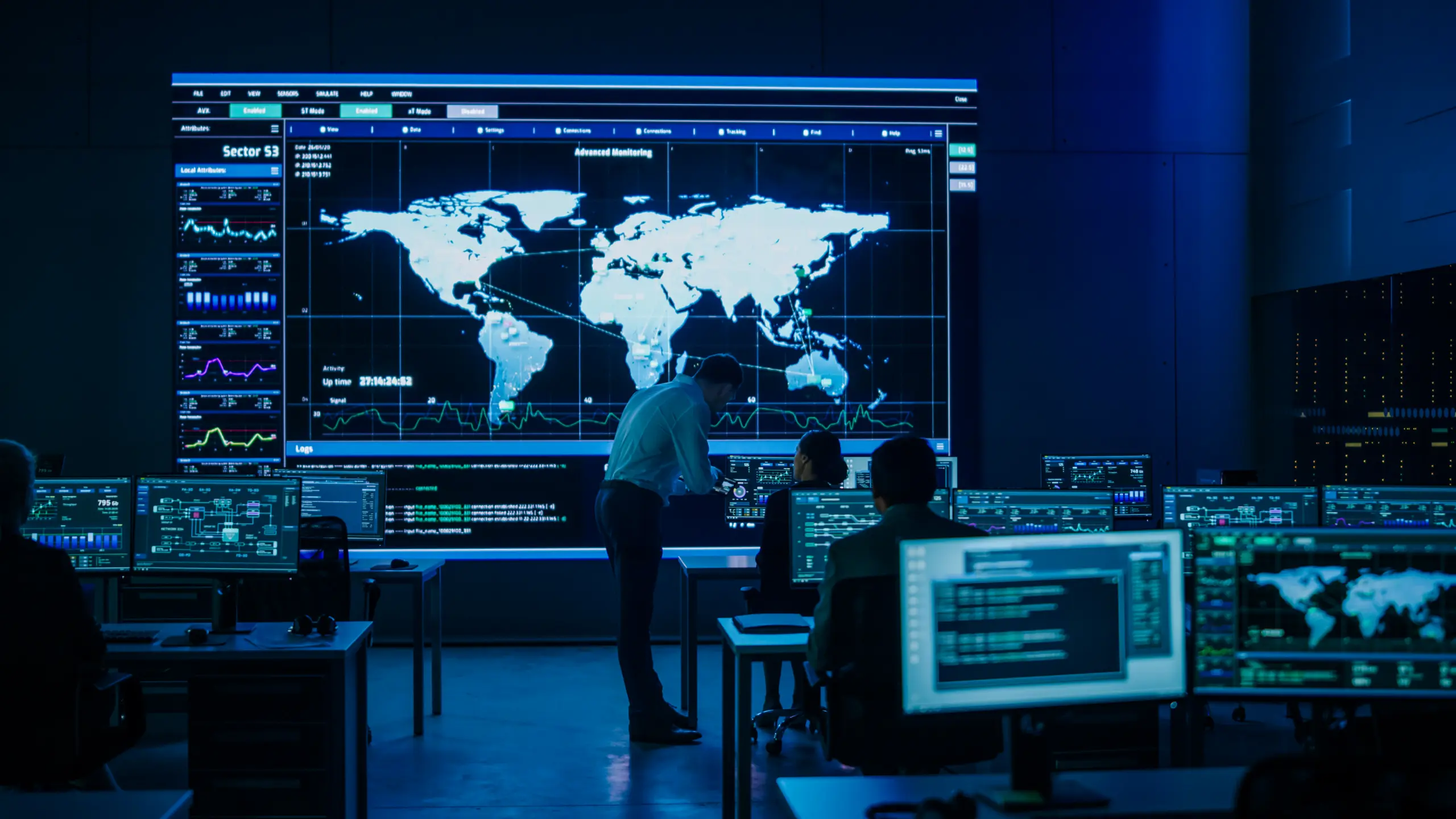Project Manager Uses Digital Tablet Talks with Colleague. Big Screen Display Showing Infographics and Global World Map Data. Telecommunications Control Monitoring Room with People Working