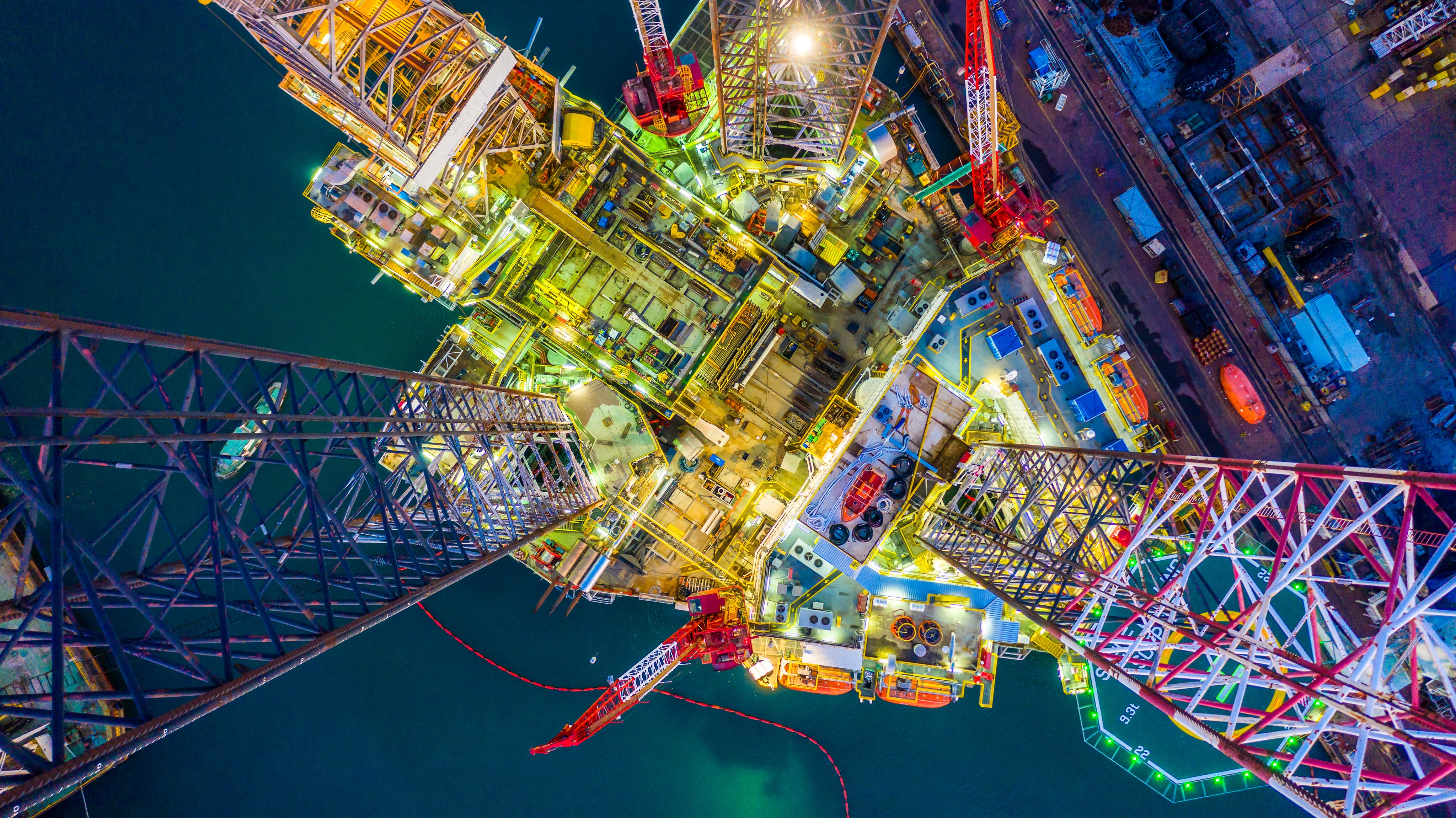 Aerial top view jack up rig under maintenance at night with blue ocean, Aerial view of jack up rig with towing vessel during towing operation, Offshore vessel in floating dock and jack up rig under repairs.