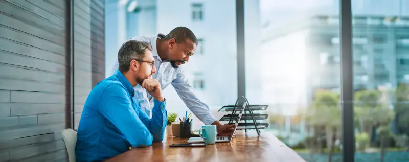 Shot of two businessmen working on a laptop in their office.