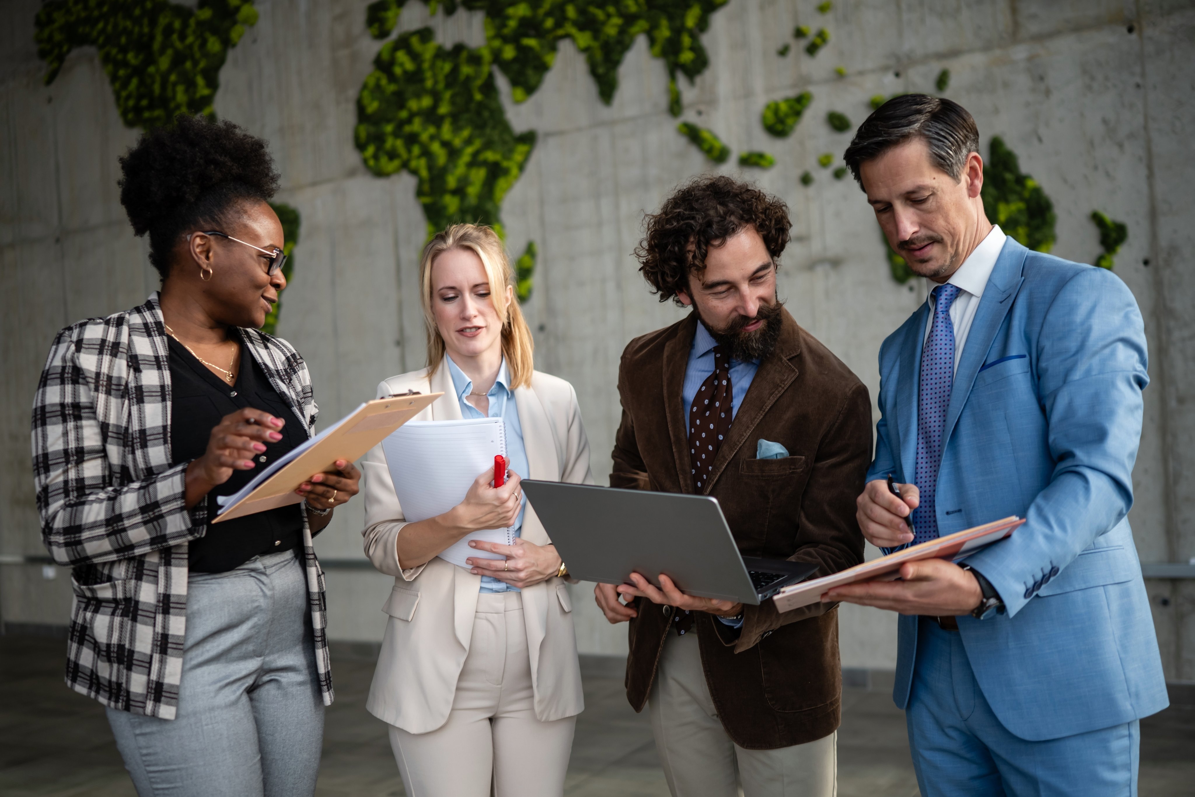 Business professionals discussing work in a modern office with a moss map wall, fostering global teamwork and innovation