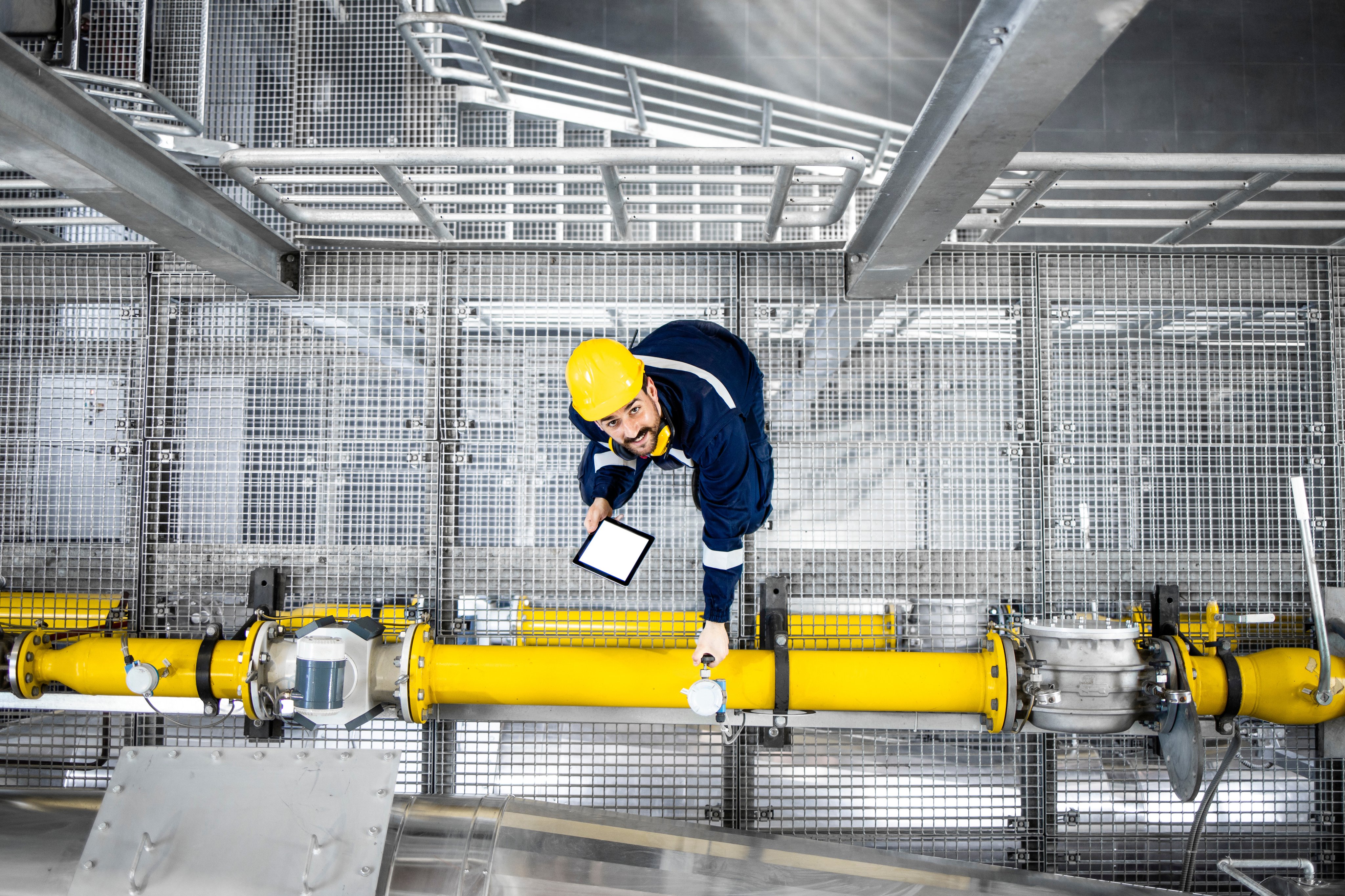 Oil and gas maintenance process and top view of refinery worker checking gas pipes on oil production platform.