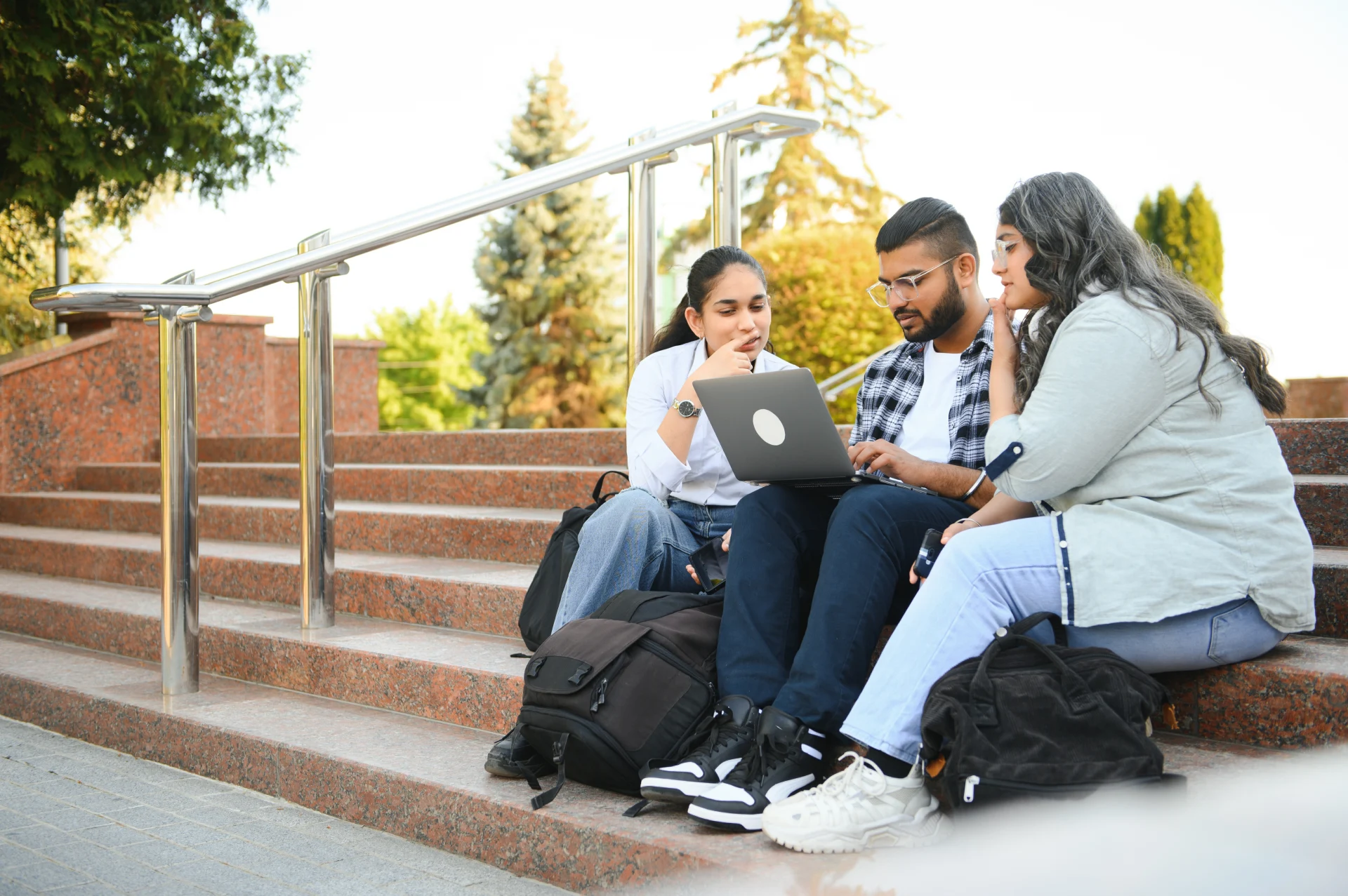 group of young students checking exam results or waiting for project approval on laptop at collage campus.