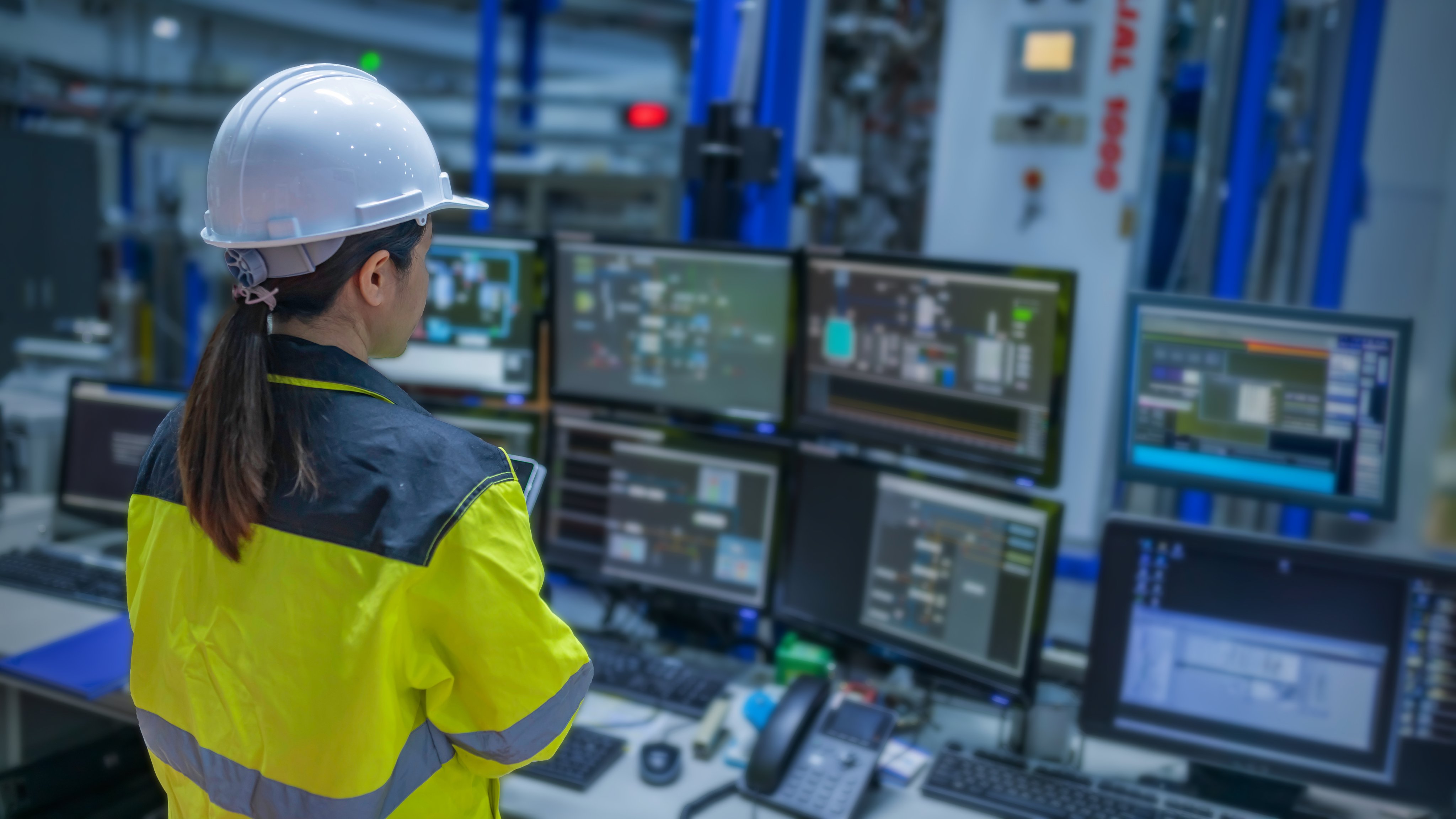Inside the large Industry Factory Female Computer Engineer Works on Personal Computer She coding program for control machine,Thailand people work on fours monitors,Programmer working with serious