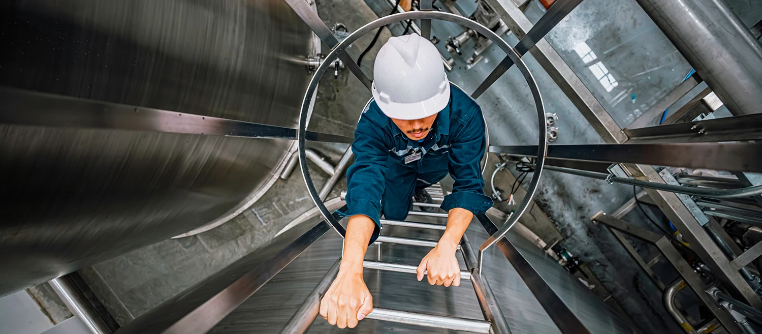 Top view male worker climbs up the ladder inspection stainless tank work at height safety