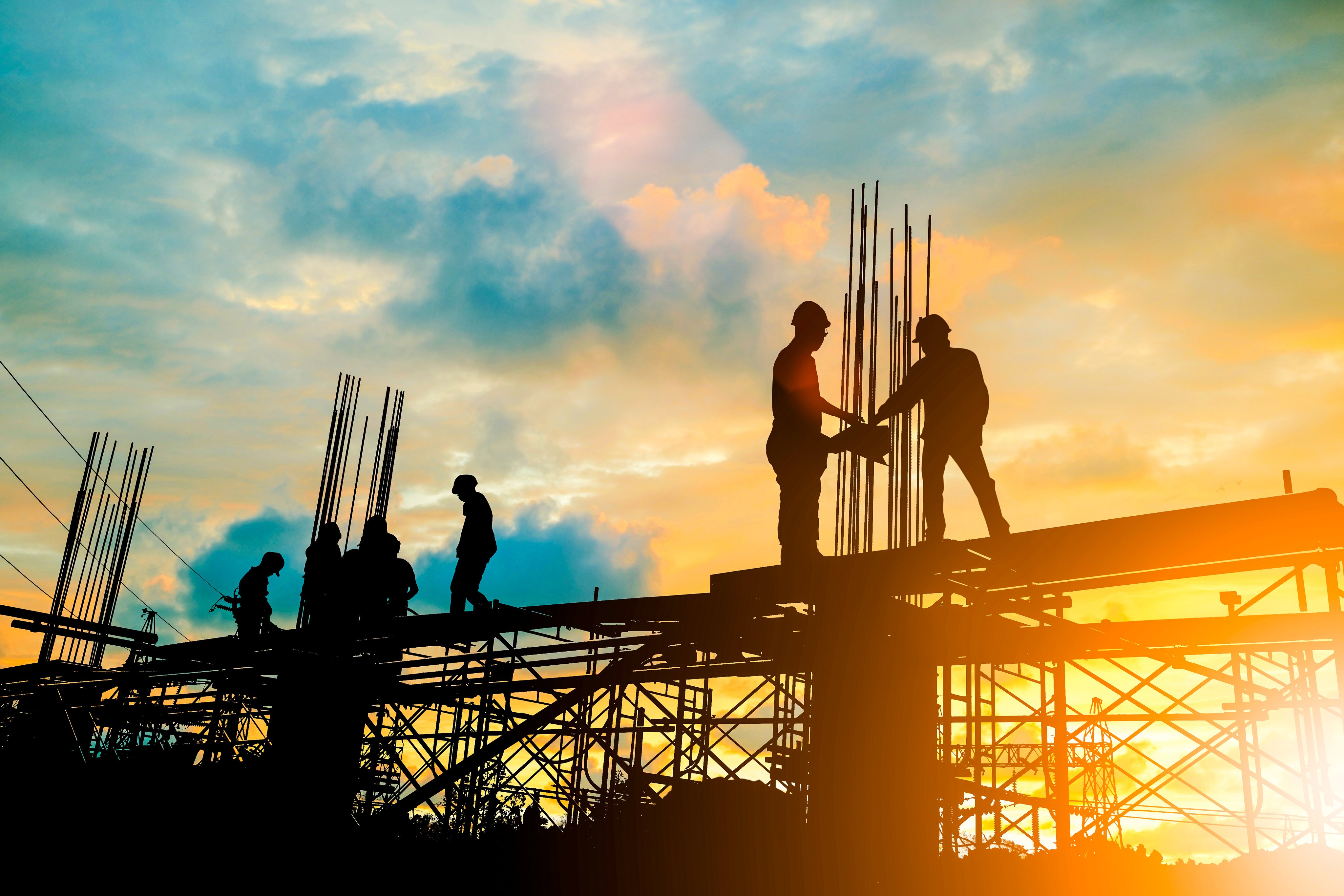 Silhouette of engineer and construction team working at site over blurred background sunset pastel for industry background with Light fair.