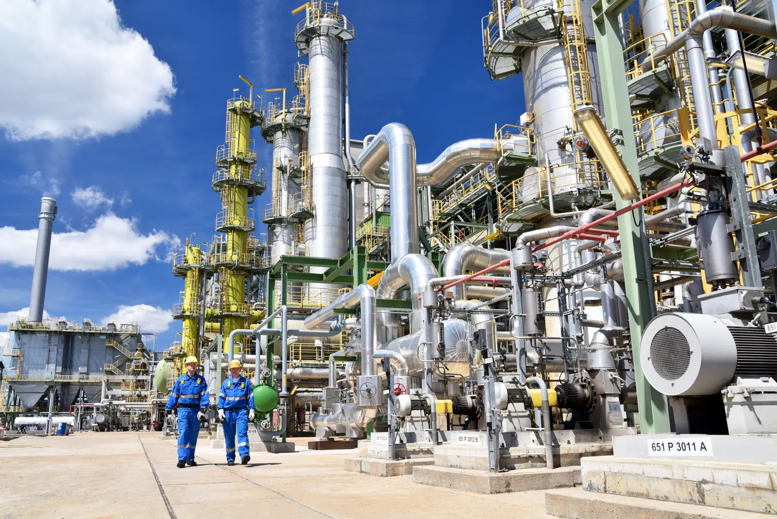 chemical industry plant - workers in work clothes in a refinery with pipes and machinery 