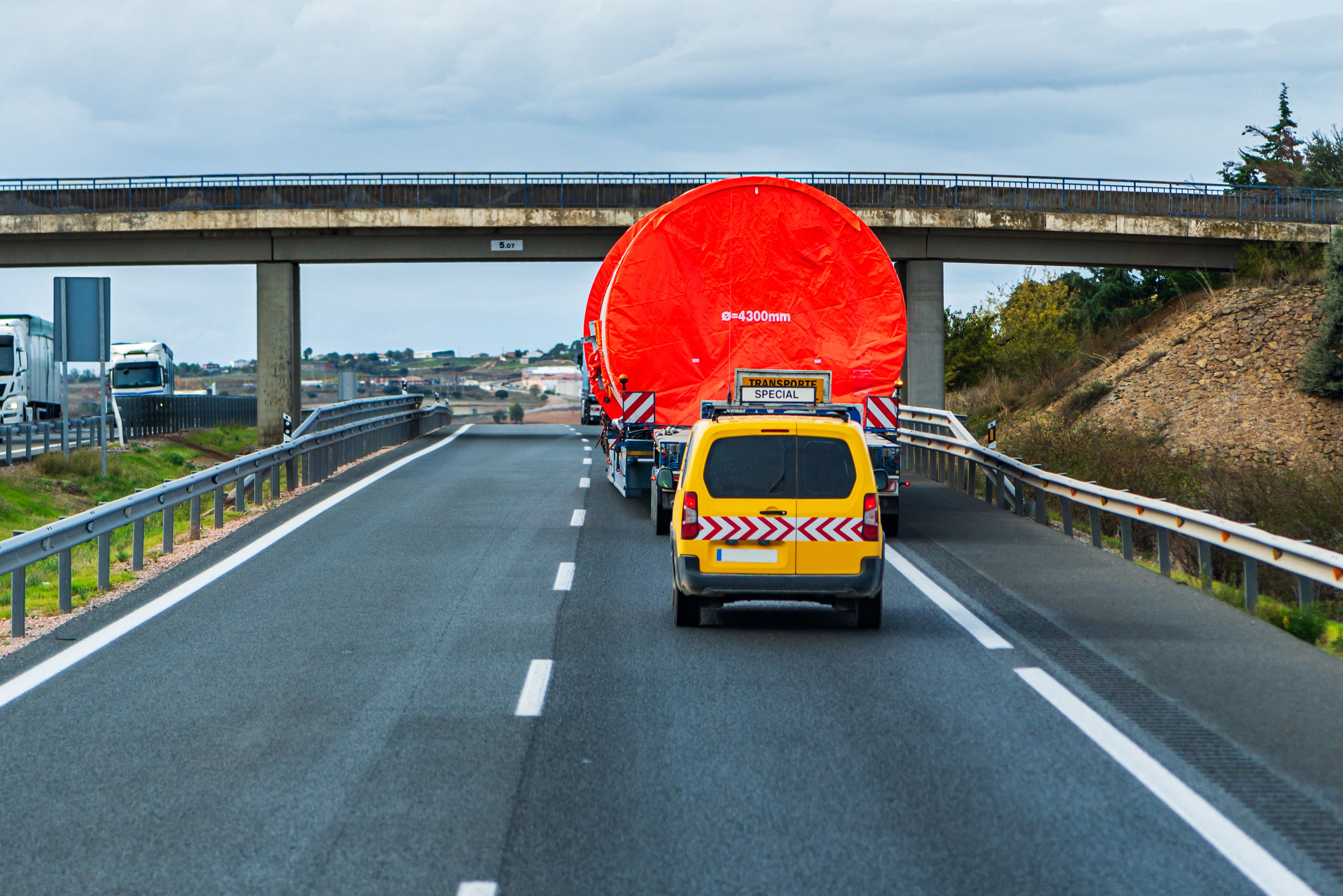 Special high-volume transport travelling on a motorway under a bridge.