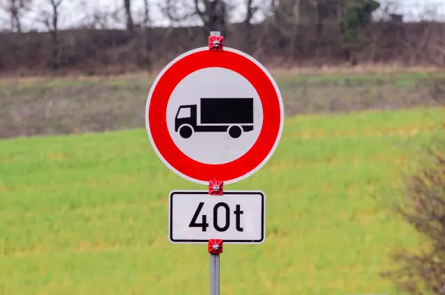 No trucks allowed sign with weight limit of 40 tons on a pole in a rural setting