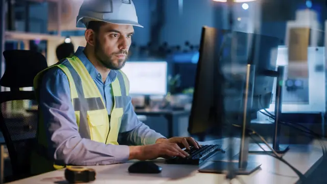 Electronics Design Factory: Portrait of Handsome Male Engineer Wearing Safety Vest Working on Computer, Developing Industrial Microchips, Semiconductor, Manufacturing Processors.
