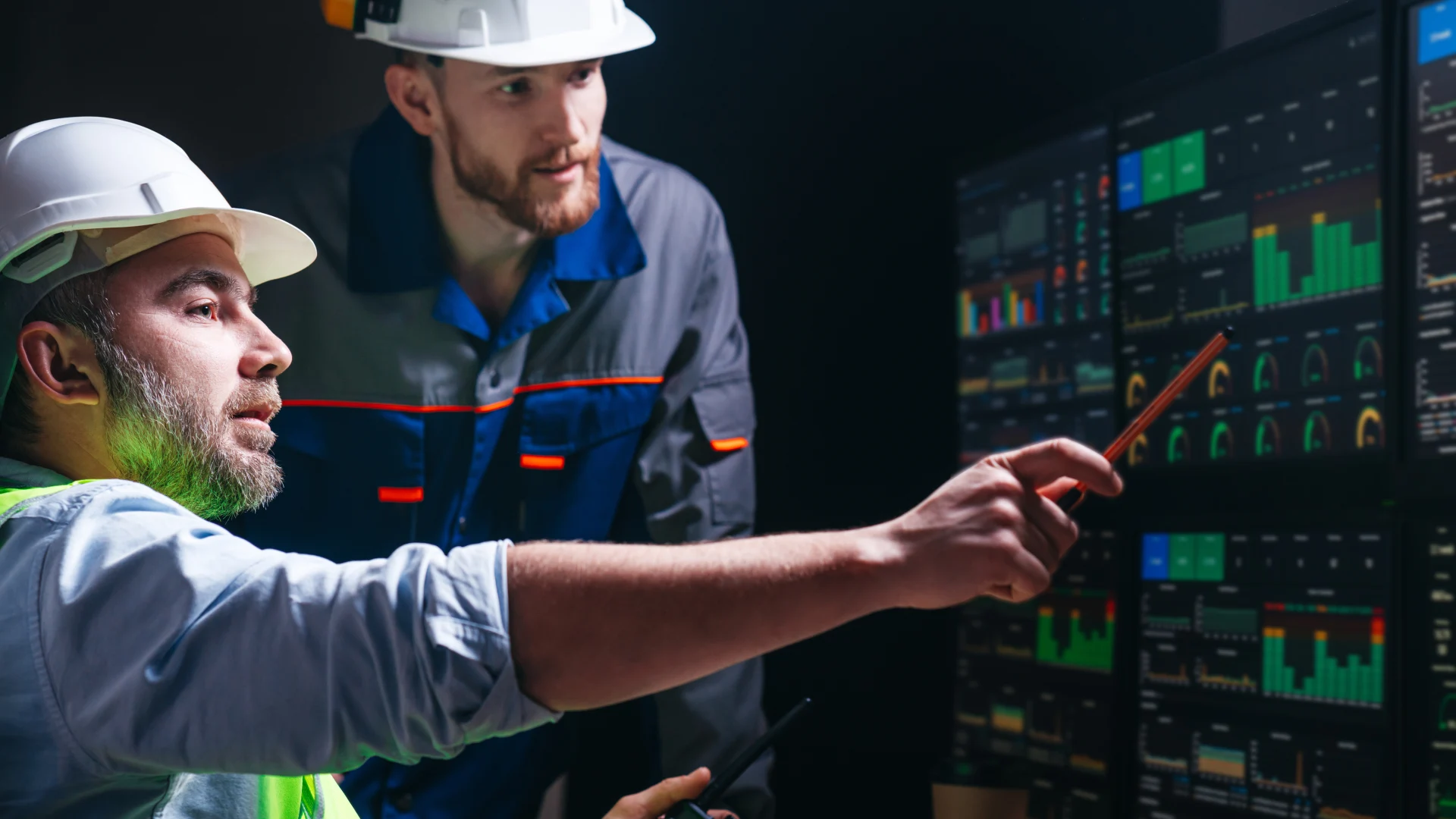 Head engineer and factory operator wearing safety vests and hard hats wollowing product process on factory uses SCADA system and industry 4.0. Two operators controll assembly line using screens with human-machine interface