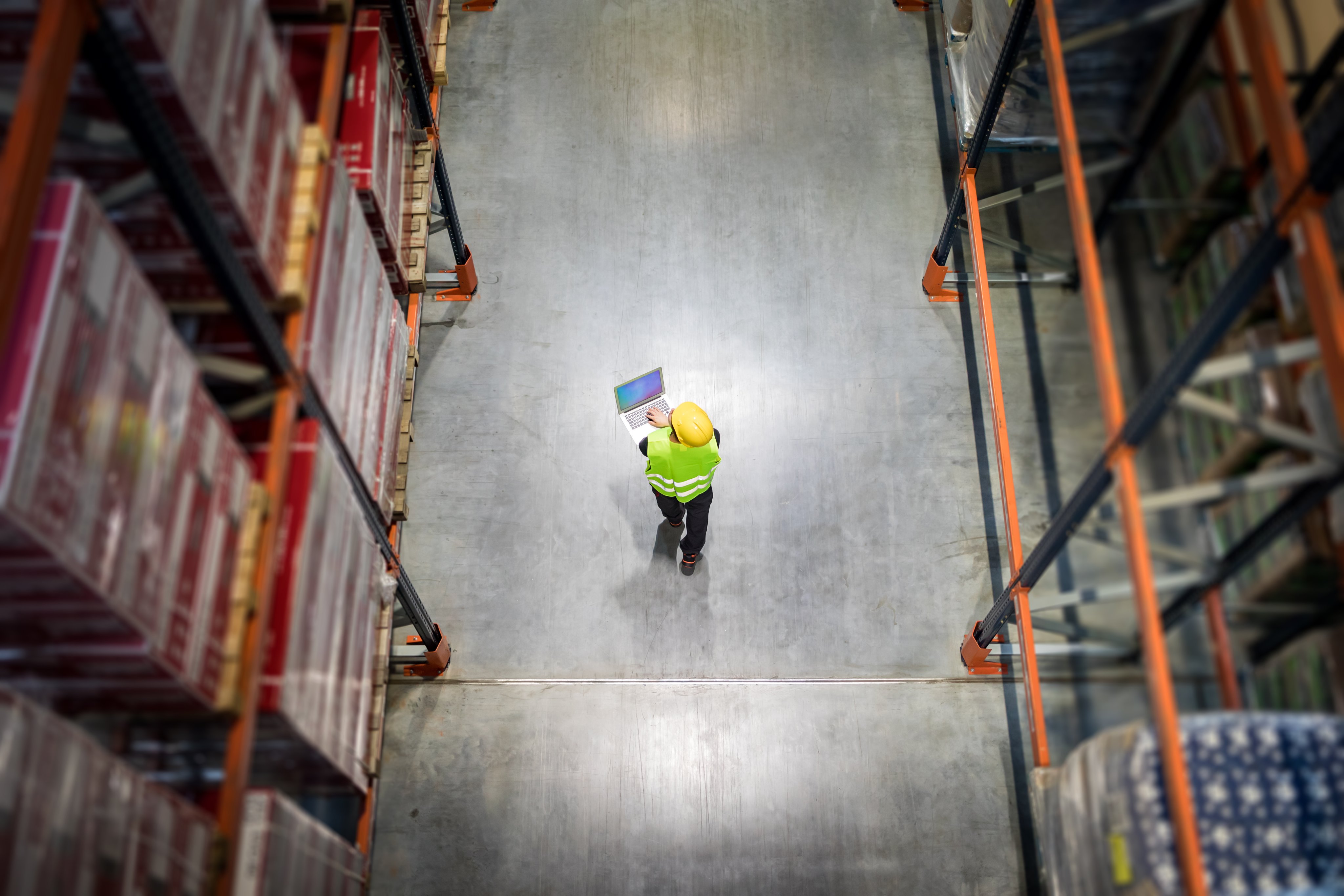 Checking warehouse database of inventory with laptop, view from above