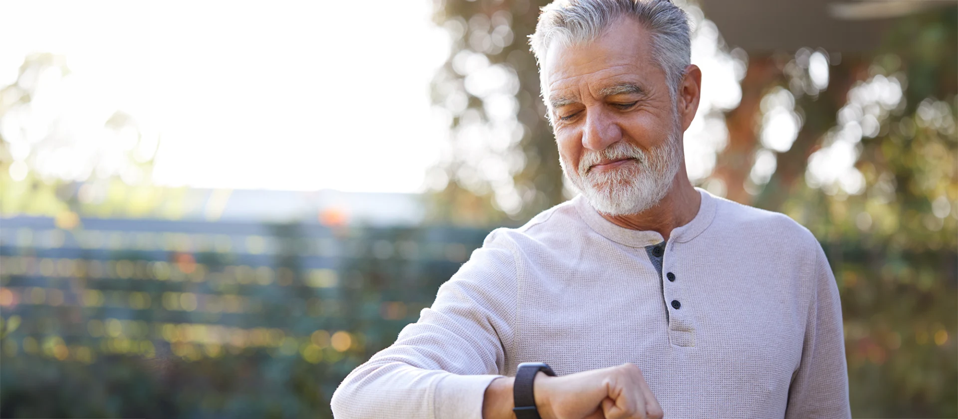 Senior Hispanic Man Checking Health Monitor On Smart Watch In Garden At Home