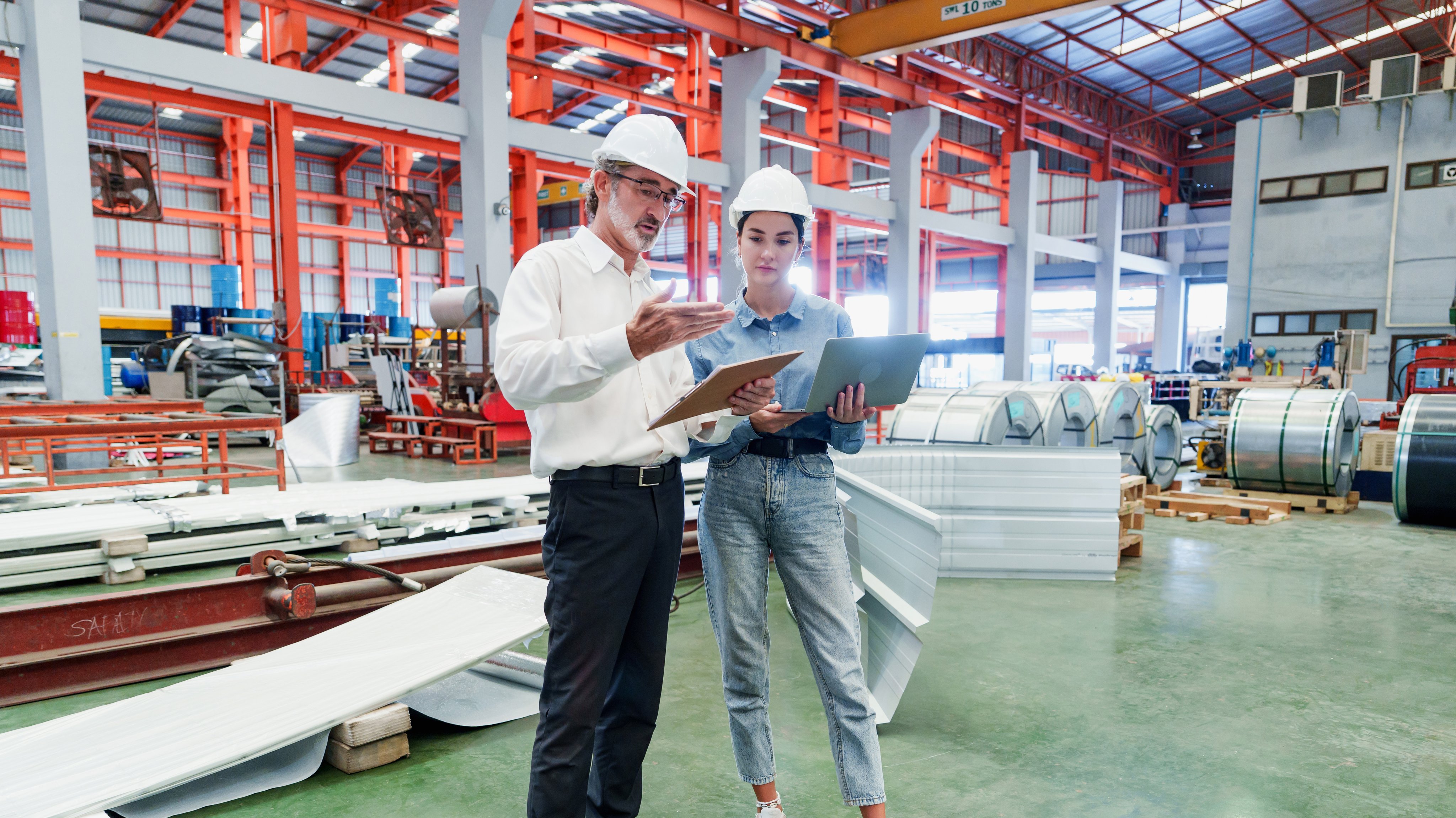 Two Caucasian men assess gray concrete floor within industrial setting. Focused examination of surface suggests detailed inspection process in warehouse environment.