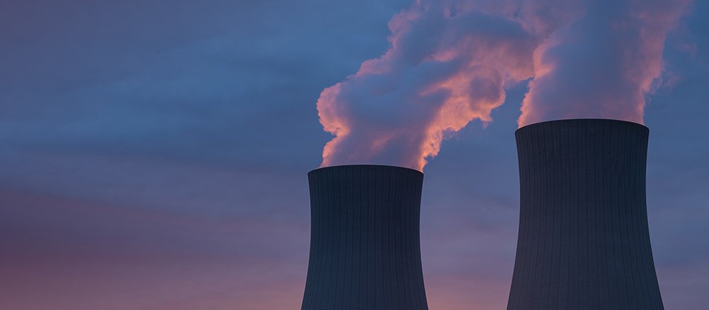 Nuclear power plant against sky at sunset