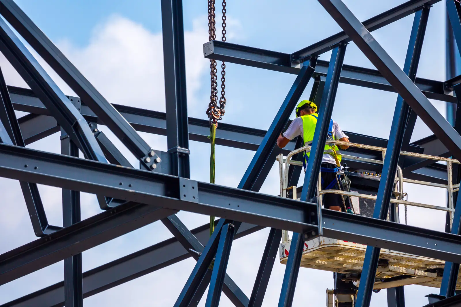 Professional installation work on a construction building site. Assemblers perform high-altitude installation works on the telescopic  boom lifts platforms. Installation of huge steel beams.