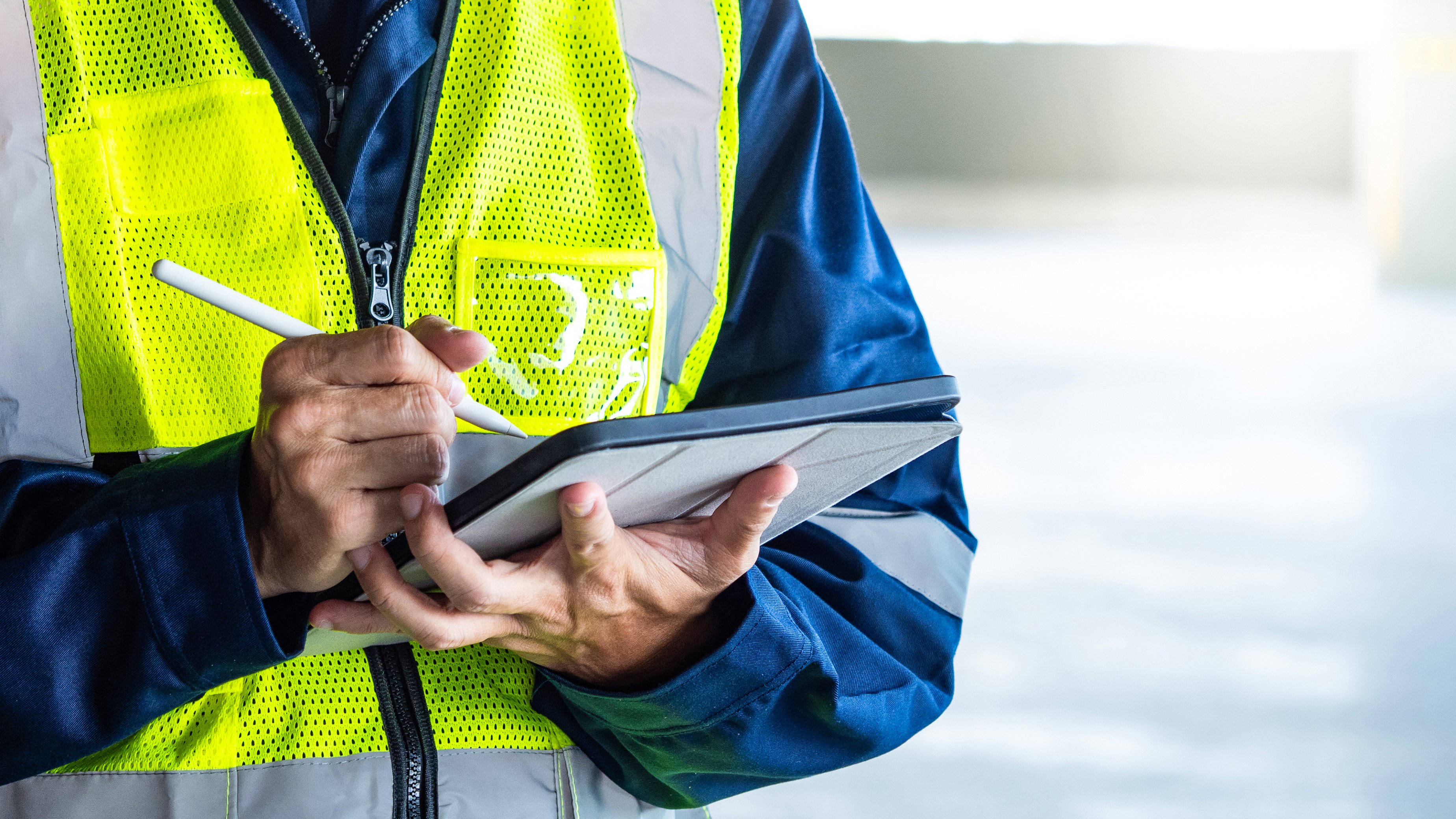 Building inspector man using digital tablet checking safety and security system in the building. Asian male worker in reflective vest working for building maintenance inspection