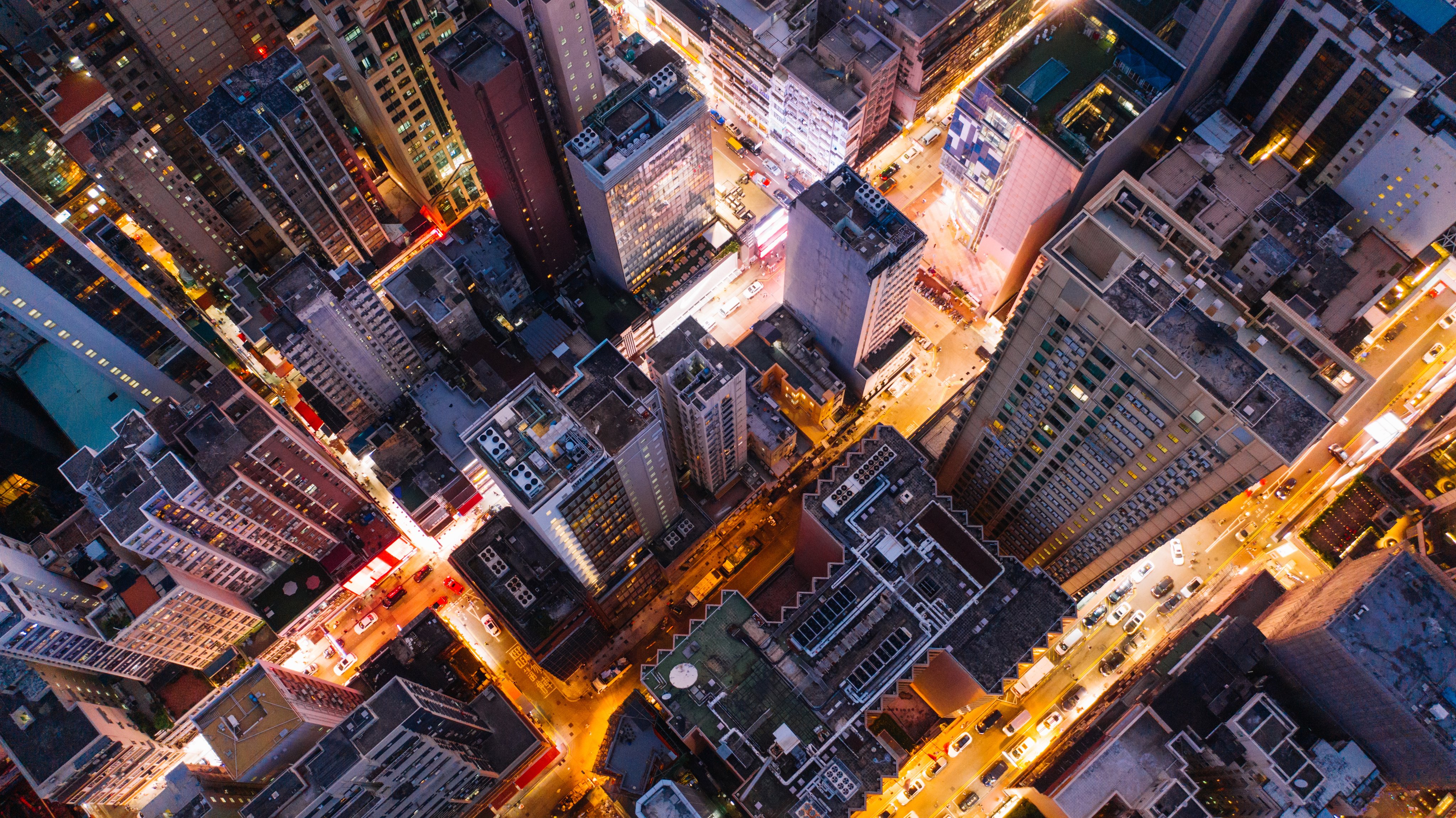 Aerial top view of downtown district  buildings in night city light. Bird's eye view from drone of cityscape metropolis infrastructure, crossing streets with parked cars. Development infrastructure