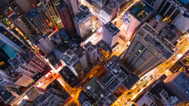 Aerial top view of downtown district  buildings in night city light. Bird's eye view from drone of cityscape metropolis infrastructure, crossing streets with parked cars. Development infrastructure