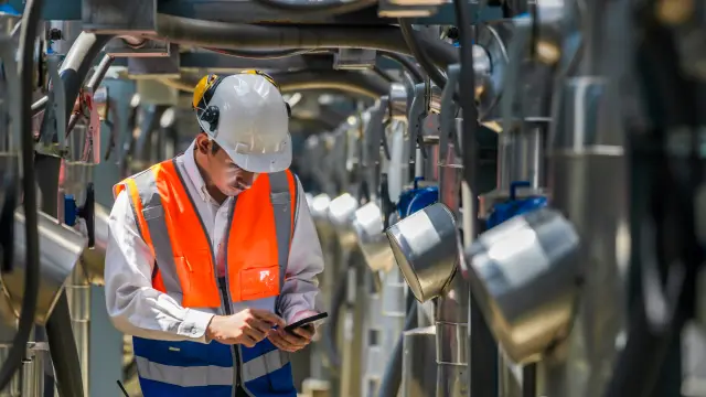 Engineers inspect gas and water pipes for power and cooling in industrial and building systems. workers in safety gear work seriously in oil and gas refining plant with pipes connecting to machinery.