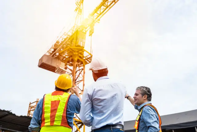 Team of male engineer construction using digital tablet for discussing of structure of building at construction site. Group of male construction builder working at construction site
