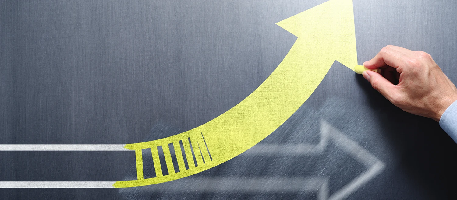 Changing business management concept. Businessman erasing white arrow and drawing yellow arrow on chalkboard.
