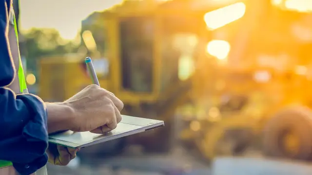Asian engineer with hardhat using  tablet pc computer inspecting and working at construction site