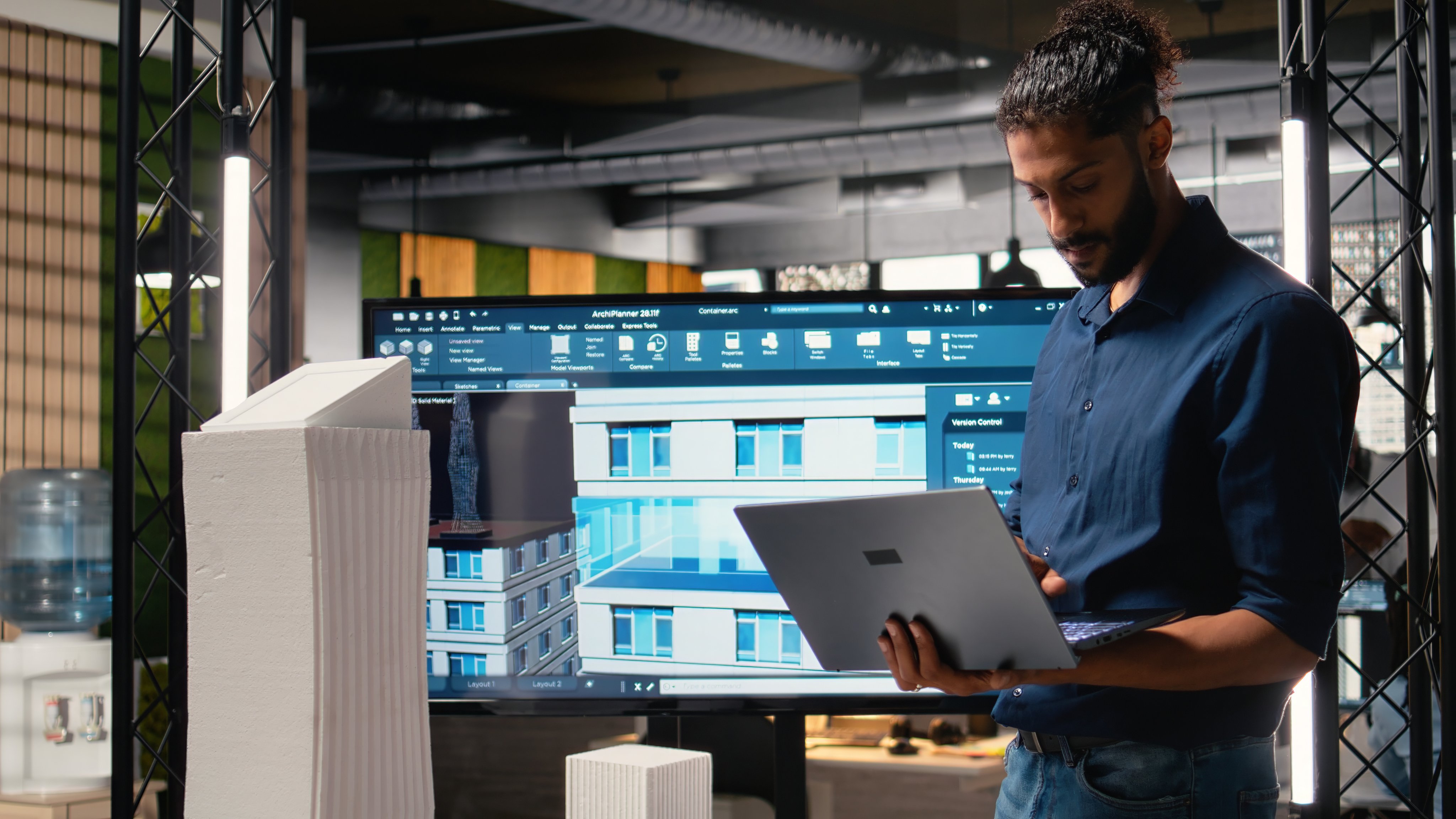 Male developer evaluating architectural 3D models and plans to find measurements and zoning regulations, collecting construction site and layout details in the office.