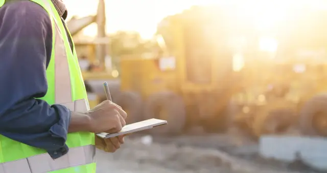 Asian engineer with hardhat using  tablet pc computer inspecting and working at construction site