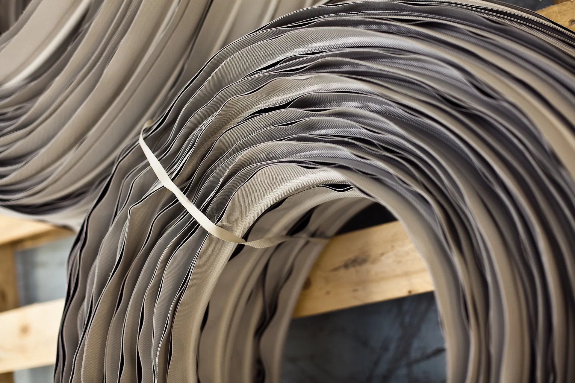 Coiled strips of woven fabric hanging on a wooden rack