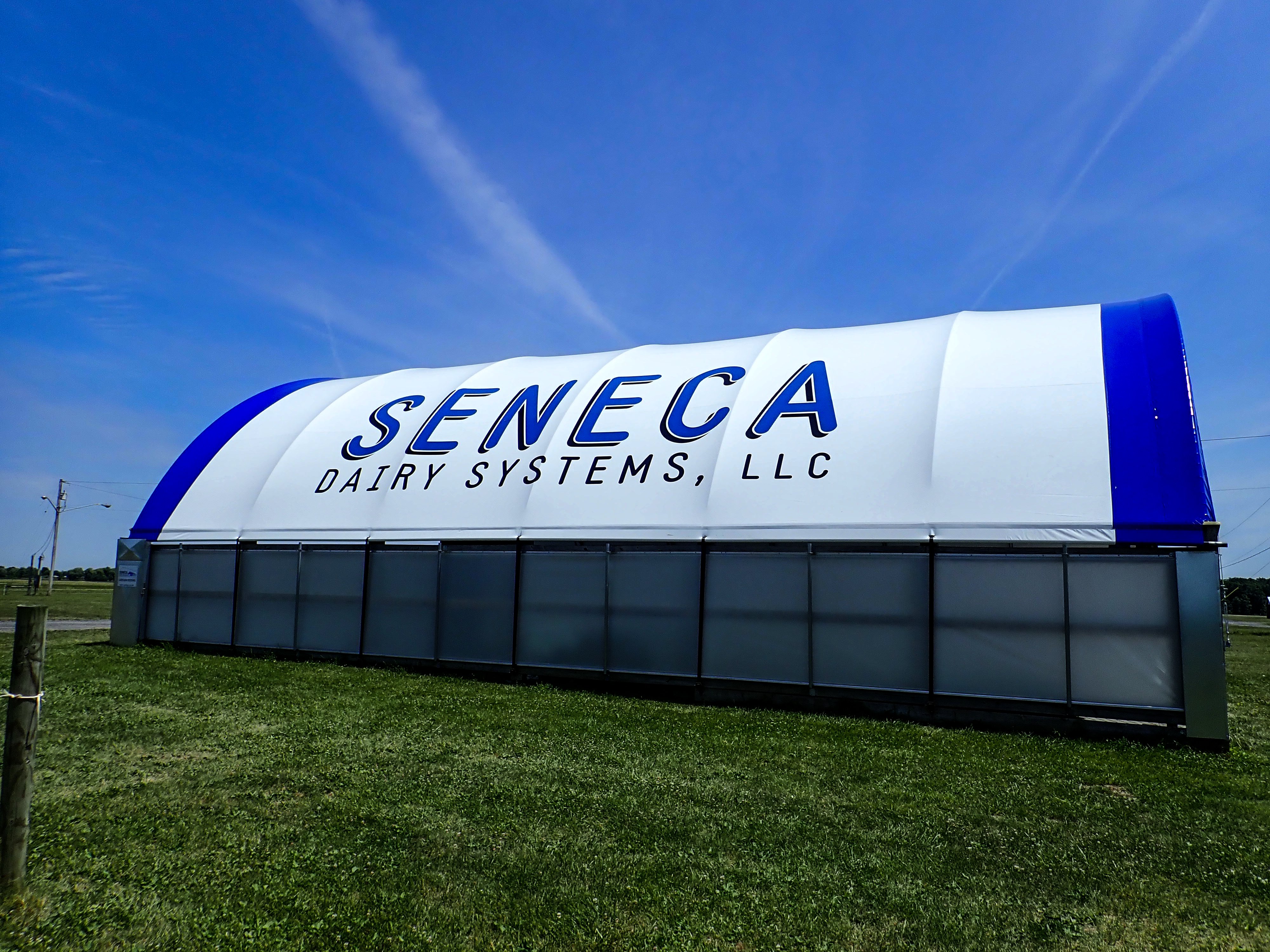 Arched fabric building with a company name printed in large letters along its white roof