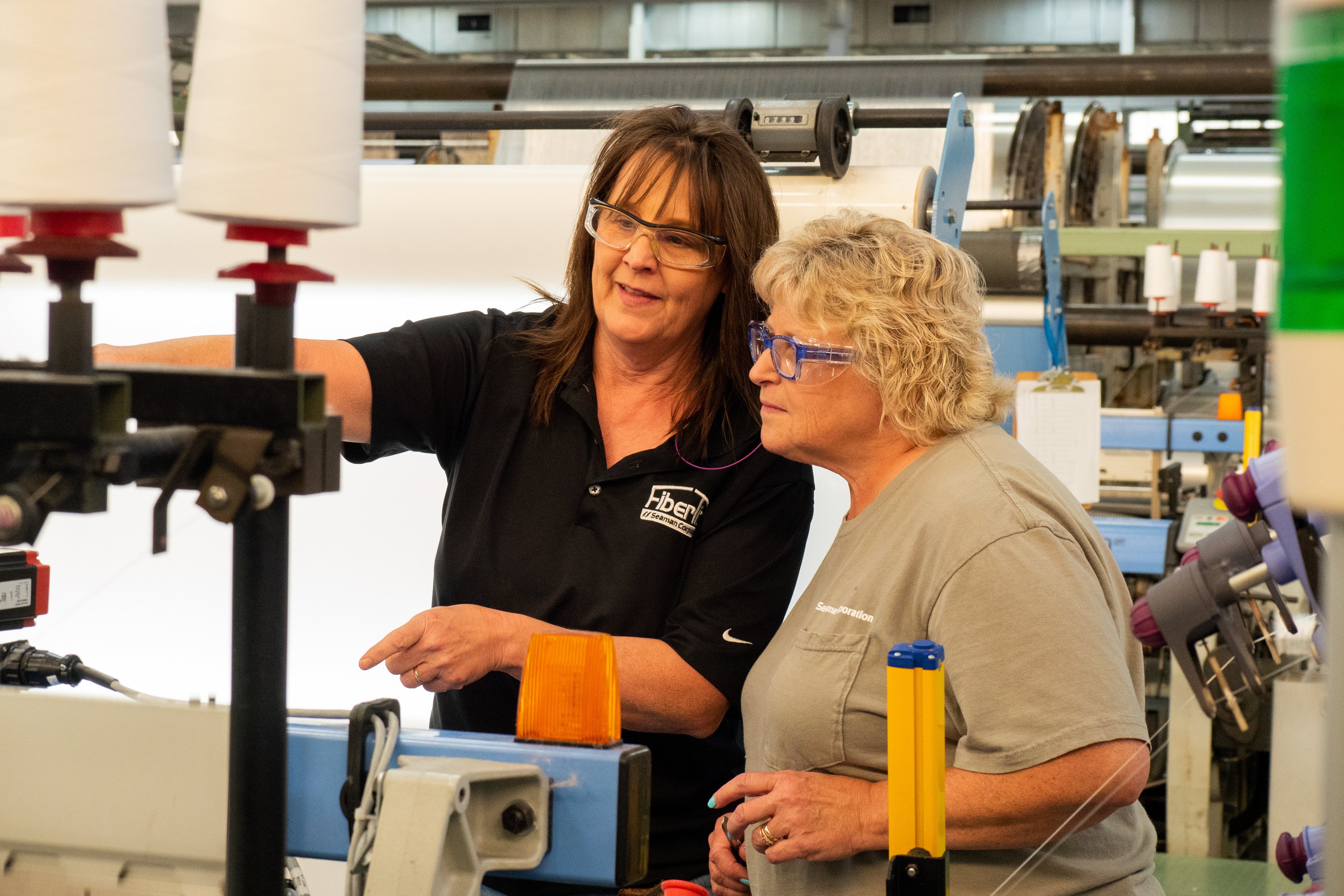 Two women working together in factory around machinery