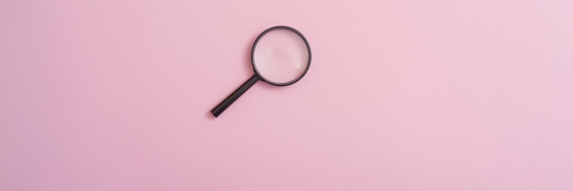 a magnifying glass on a pink background