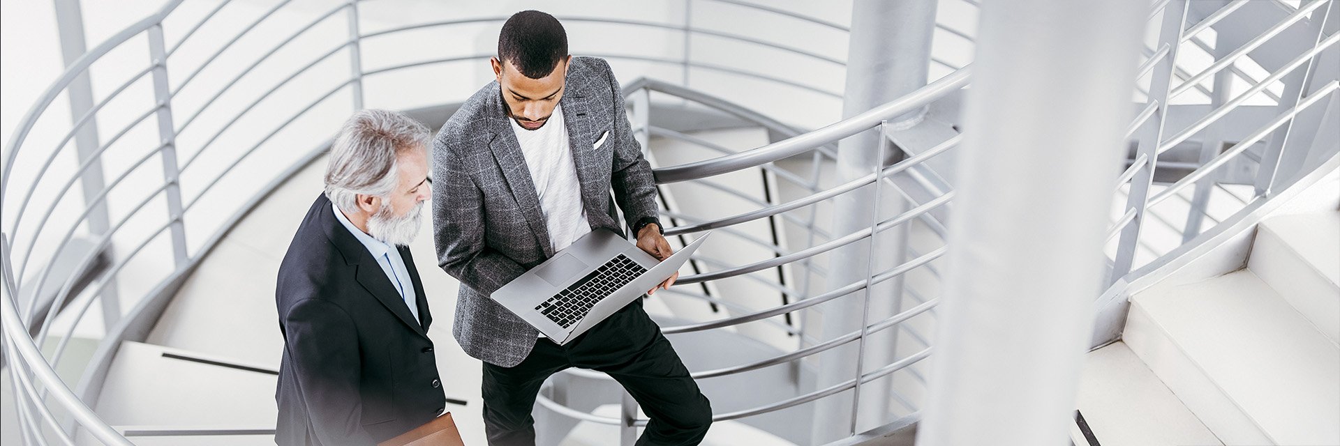 two-business-men-looking-at-laptop-on-stairs
