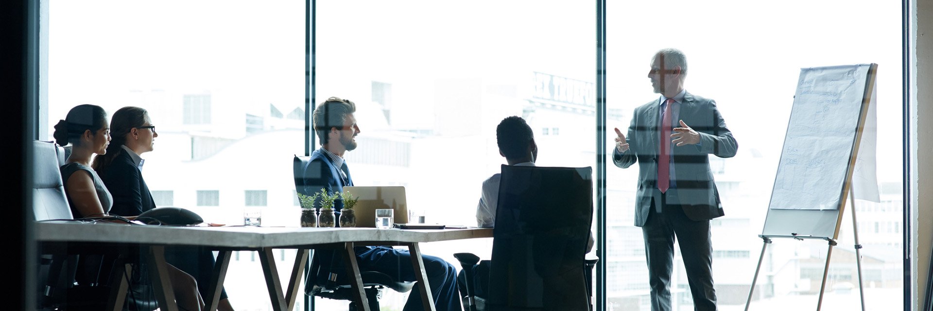 man-presenting-to-team-glass-room