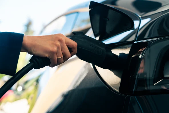 Electric vehicle charging port plugged into blue EV battery charger