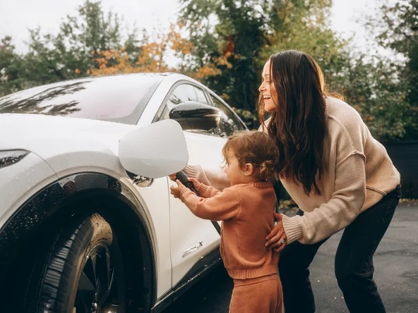 woman with her child charging electric vehicle 