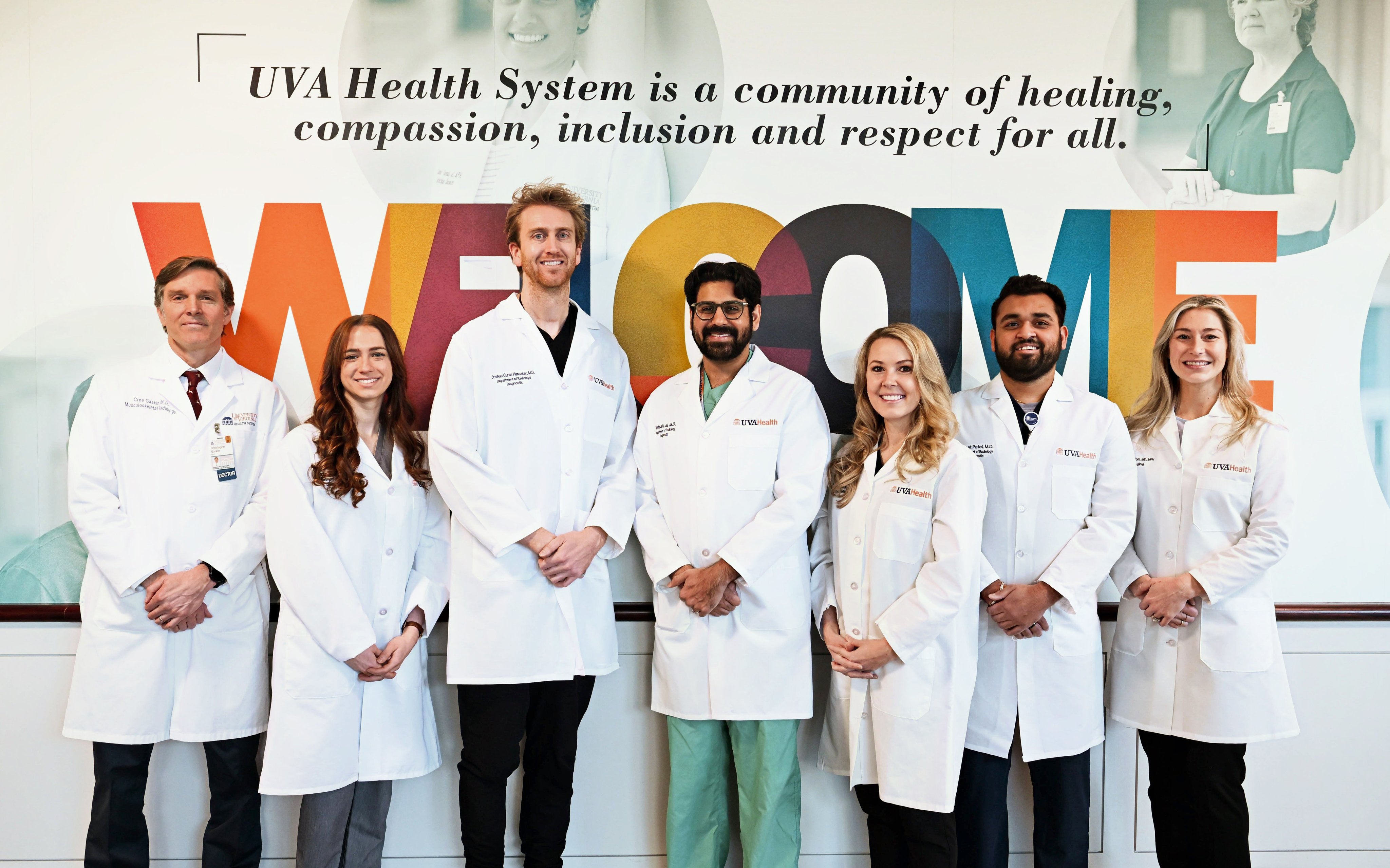 Radiology residents and faculty standing in front of sign reading: WELCOME: UVA Health System is a community of healing, compassion, inclusion and respect for all