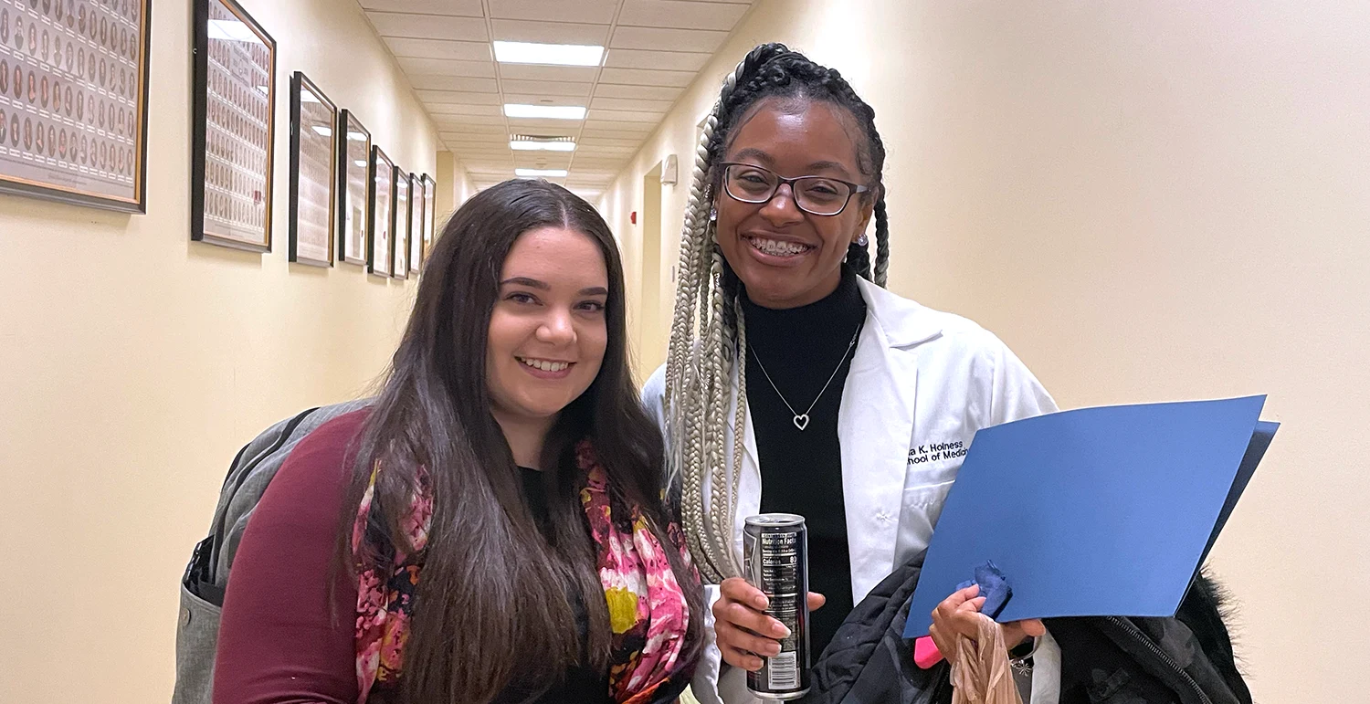Two female graduate students smiling, holding certificates for advancing to candidacy.